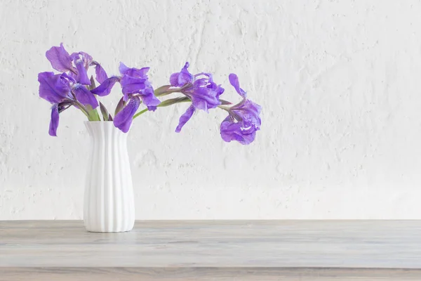 Iris dans un vase sur fond blanc vieux mur — Photo