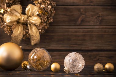 Koyu ahşap arka planda Noel altın topları ve çelenk 