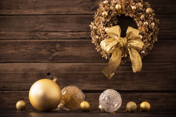 Bolas de oro de Navidad y corona sobre fondo de madera oscura —  Fotos de Stock