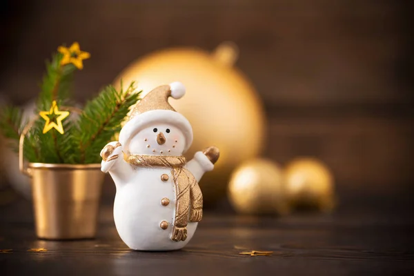 Decorações douradas de Natal e boneco de neve em backgrou de madeira escura — Fotografia de Stock