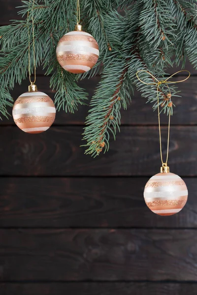 Weihnachtskugeln auf Tannenzweigen auf dunklem Holzgrund — Stockfoto