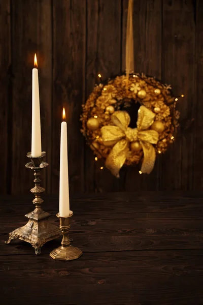 Two candles in candlesticks on background Christmas wreath on da — Stock Photo, Image