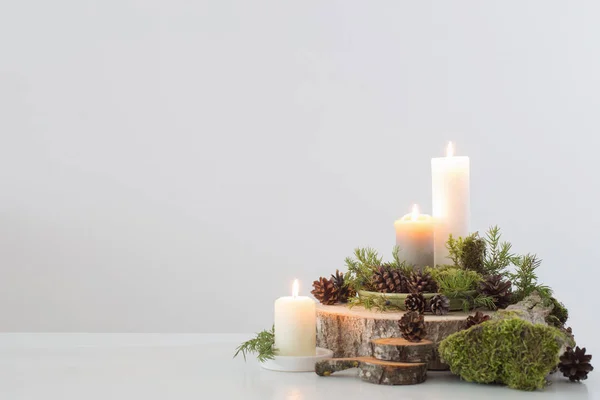 Brennende Kerzen auf Säge mit Zapfen und Zweigen auf weißem Hintergrund — Stockfoto