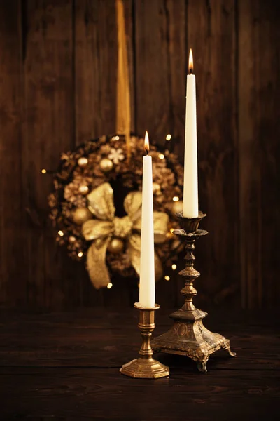 Two candles in candlesticks on background Christmas wreath on da — Stock Photo, Image
