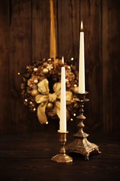 Two candles in candlesticks on background Christmas wreath on da Stock Image