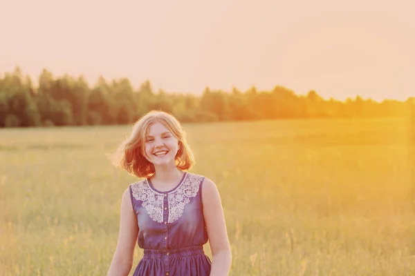 Tiener meisje in de zomer veld bij zonsondergang — Stockfoto