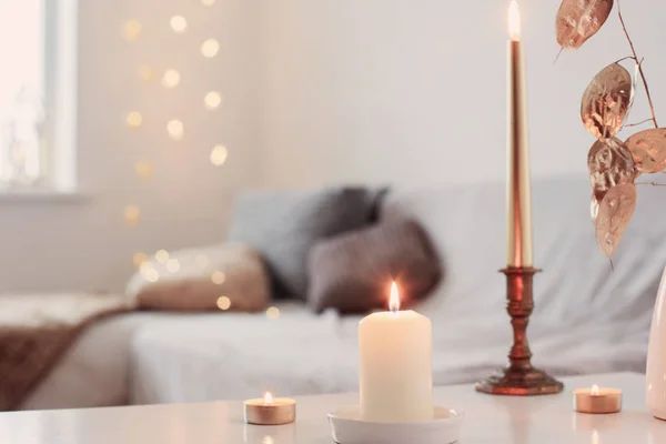 Burning candles on table in white interior — Stock Photo, Image