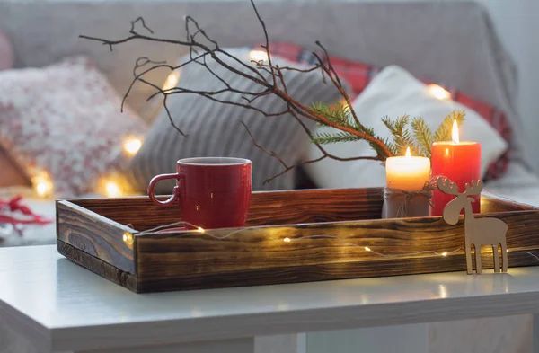 Red cup of tea on tray with burning candles on background sofa w — Stock Photo, Image