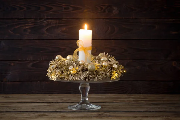 Corona de oro de Navidad con vela encendida en la espalda de madera oscura — Foto de Stock