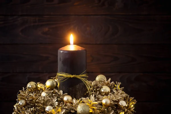 Χριστουγεννιάτικο χρυσό στεφάνι με μαύρο αναμμένο κερί σε σκούρο ξύλινο — Φωτογραφία Αρχείου