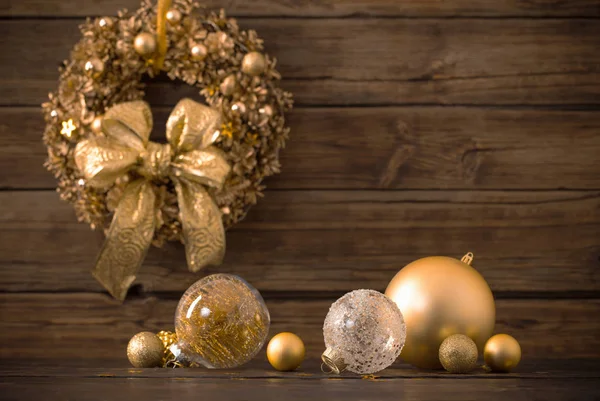 Boules d'or de Noël et couronne sur fond de bois foncé — Photo