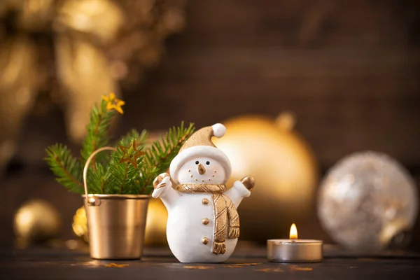 Christmas golden decorations and snowman on dark wooden backgrou