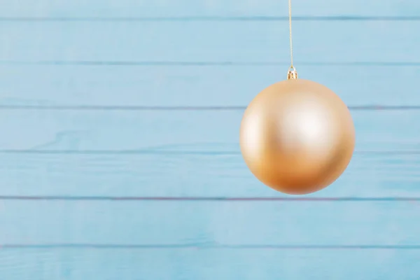 Christmas golden ball hanging  on  blue wooden background