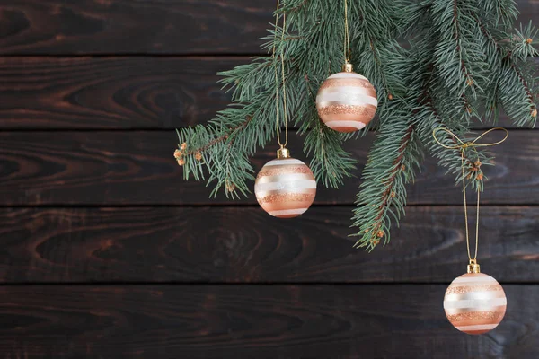 Weihnachtskugeln auf Tannenzweigen auf dunklem Holzgrund — Stockfoto