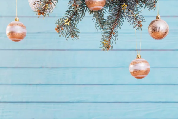 Weihnachtskugeln auf Tannenzweigen auf blauem Holzgrund — Stockfoto