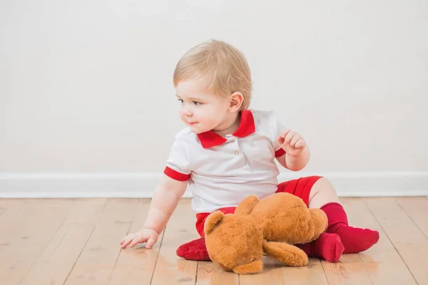 Lindo sorriso bebê com ursinho de pelúcia no chão de madeira — Fotografia de Stock