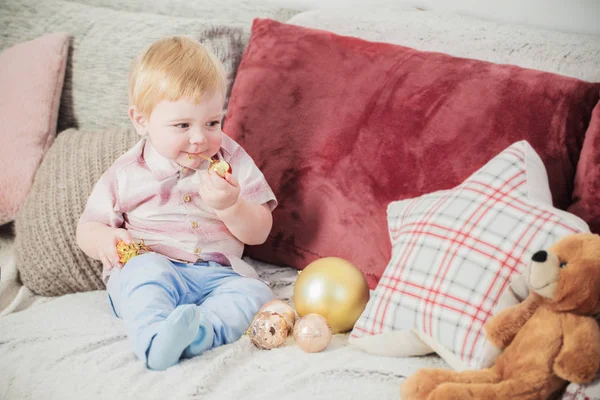 Ребенок с рождественскими шарами и игрушками на диване — стоковое фото