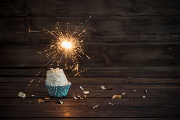 Birthday cake with sparkler on old wooden background — Stock Photo, Image