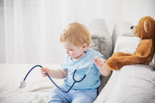 Little child plays doctor with teddy bear at home — Stock Photo, Image