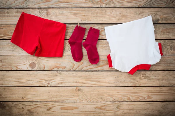 Ropa de bebé colgando de la cuerda sobre fondo de madera — Foto de Stock