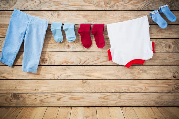 Ropa de bebé colgando de la cuerda sobre fondo de madera — Foto de Stock