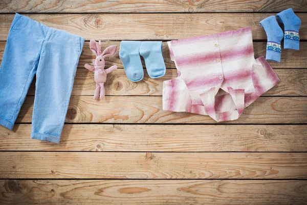 Ropa de bebé colgando de la cuerda sobre fondo de madera — Foto de Stock