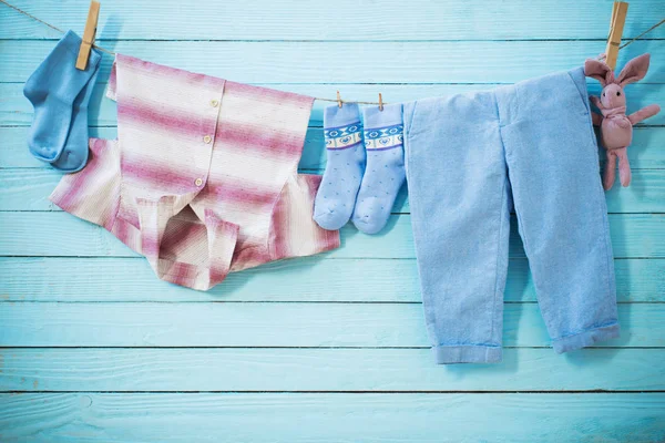 Ropa de bebé colgando de la cuerda sobre fondo de madera — Foto de Stock