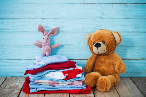 Ropa de bebé y oso de juguete sobre fondo de madera viejo — Foto de Stock