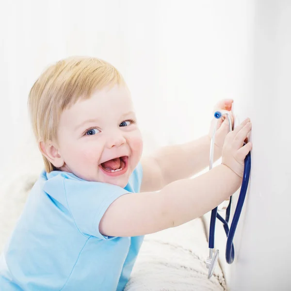 Criança brinca de médico com estetoscópio em casa — Fotografia de Stock