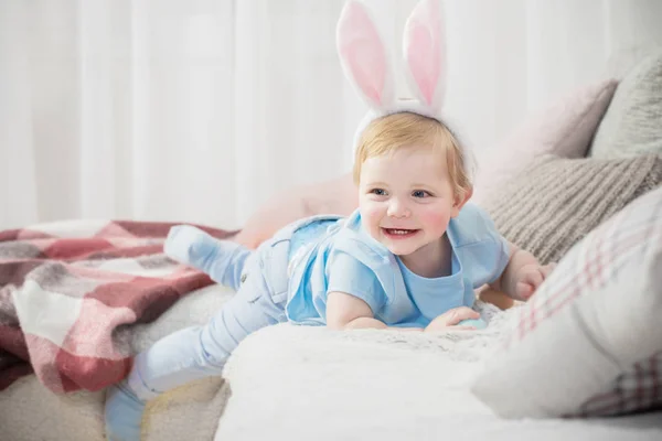 Schöner kleiner Junge in Hasenohren mit Ostereiern auf der Couch — Stockfoto