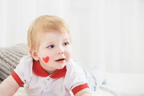 Menino bonito com coração pintado em sua bochecha — Fotografia de Stock