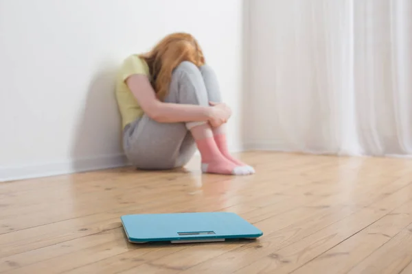 悲しい10代の女の子とスケール上の木製の床 — ストック写真