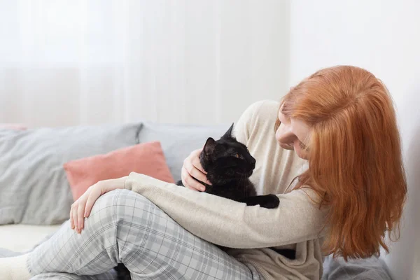 Hermosa adolescente chica con negro gato en cama en casa — Foto de Stock