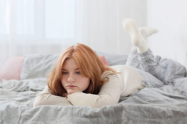 Beautiful sad blonde teenager girl on bed at home — Stock Photo, Image