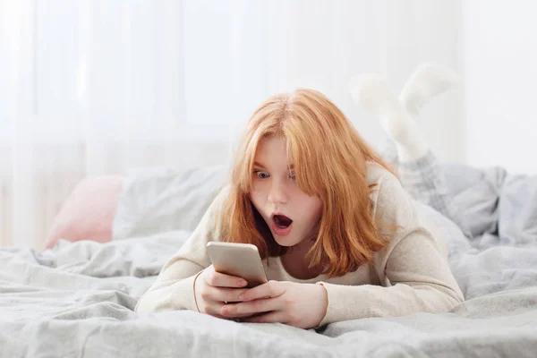 Tiener meisje met smartphone op bed — Stockfoto