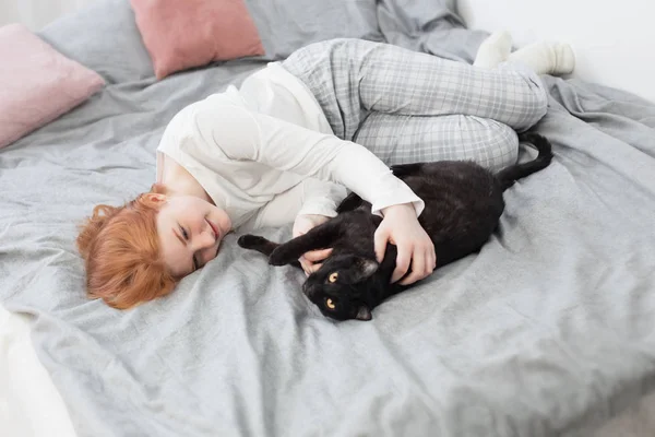 Vacker tonåring flicka med svart katt på sängen hemma — Stockfoto