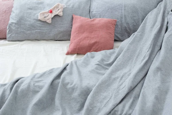 Cama com roupa de cama cinza e máscara de sono — Fotografia de Stock