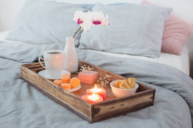 Kahve, tatlılar, mumlar, çiçekler ve korse yatakta tahta tepside