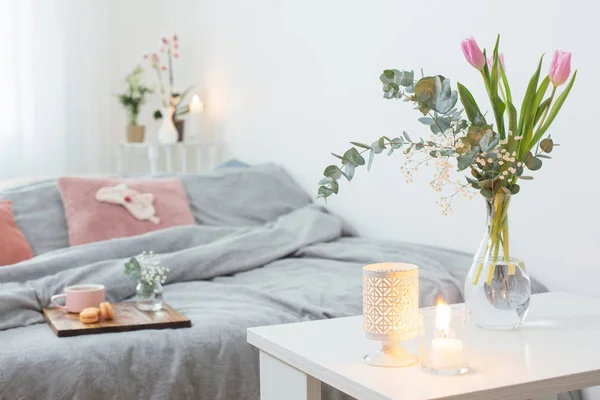 Interieur van slaapkamer met bloemen, kaarsen en kopje thee — Stockfoto