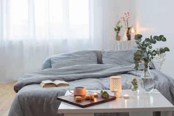 Wnętrze sypialni z bukietem, świecami i filiżanką herbaty — Zdjęcie stockowe