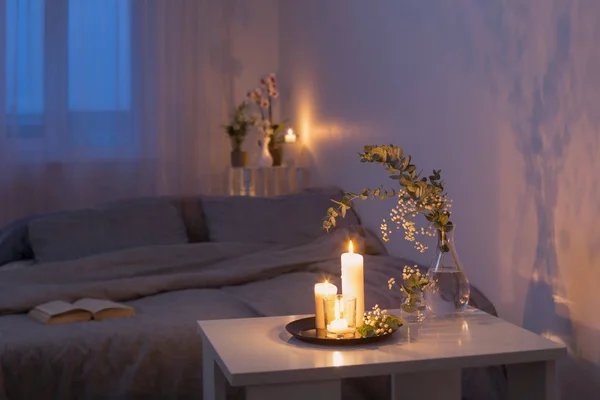 Nocne wnętrze sypialni z kwiatami i płonącymi świecami — Zdjęcie stockowe