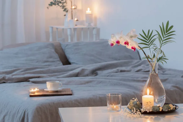 Schlafzimmerinnenraum mit Blumen und brennenden Kerzen — Stockfoto