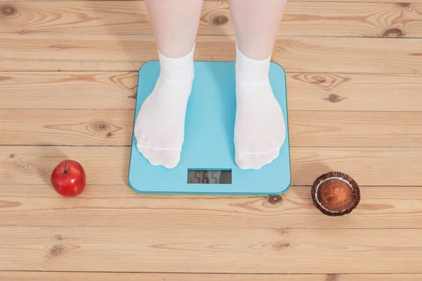 Female legs apple and cake, and  electronic scales on  wooden fl — Stock Photo, Image