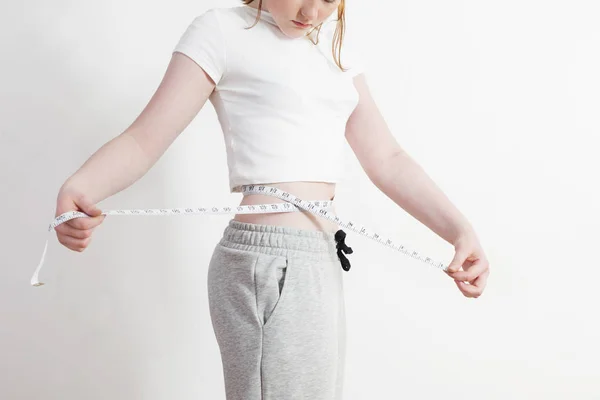Mujer muestra pérdida de peso en fondo pared blanca — Foto de Stock