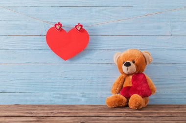 Ahşap arka planda kırmızı kalpli oyuncak ayı. Sevgililer Günü 