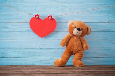 Ahşap arka planda kırmızı kalpli oyuncak ayı. Sevgililer Günü 