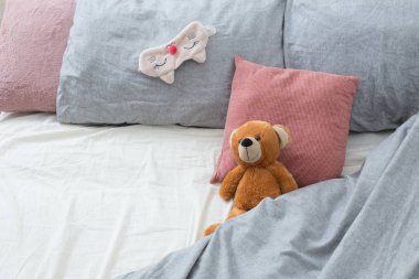 bed with teddy bear on gray linens  clipart