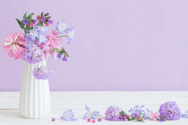 Modré a růžové květiny v vázu na bílém stole — Stock fotografie