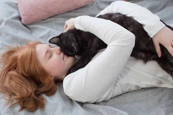 Όμορφη έφηβη κοπέλα με μαύρη γάτα στο κρεβάτι στο σπίτι — Φωτογραφία Αρχείου