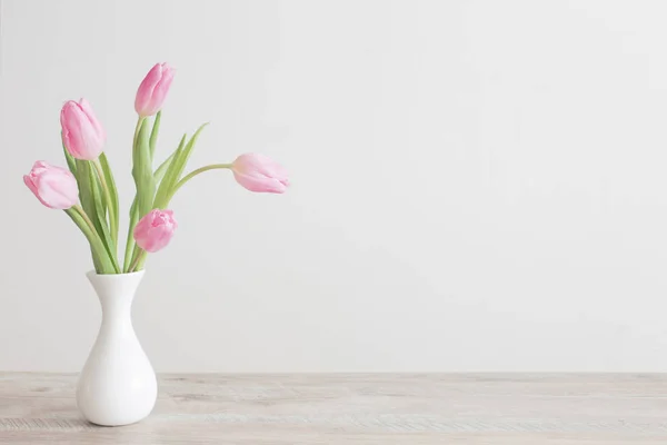 Tulipanes rosados en jarrón de cerámica blanca sobre mesa de madera sobre fondo —  Fotos de Stock